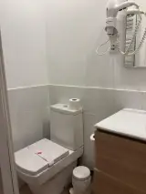Inodoro del baño del Apartamento Exterior con papel higiénico y secador de pelo mural en la pared